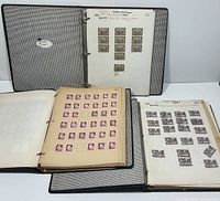 Three black binders opened displaying pages of Canadian stamps including blue, green, pink/red stamps various years and designs