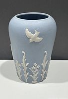 Front and side view of light blue pottery vase with raised white bird and floral decoration.