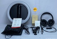 Full lot showing foldable Mobifoto ring light, wireless over-ear headset, USB webcam with tripod, cables and user manuals