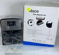 Front view of Kbice nugget ice maker wrapped in plastic alongside original box and printed manual on white background.