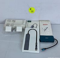 All items in the tech bundle including two USB-C wall chargers in packaging, UGREEN 5-in-1 USB-C adapter in packaging, and BENFEI USB-C hub with its box.