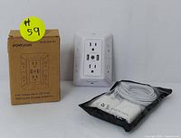 Wall-mounted outlet extender and box alongside a sealed long white USB cable and two white USB wall chargers.