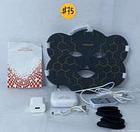 Black flexible LED face mask with gold hexagonal pattern, accompanied by user manual, white power bank, white USB wall adapter, USB charging cables, wired remote controller, and three pairs of black eye protectors.