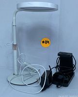 Front view of USB LED desk lamp, wireless charging base, and power adapter with cords visible on a white surface.