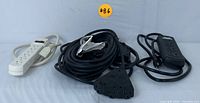 Full view of all four power accessories: two black heavy-duty extension cords, one white 6-outlet surge protector, one black 3-outlet power strip.