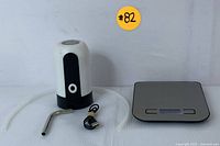 Electric water dispenser with hose, USB cable, and digital kitchen scale seen together on a white background.