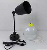 Photo showing the black adjustable desk lamp alongside the Ecozy wake-up light with power cords.