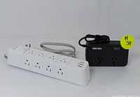 White home surge protector power strip with four AC outlets and multiple USB ports with fabric wrapped power cord.
