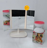 Frontal view of the open tri-fold LED vanity mirror and electric makeup brush cleaner with box