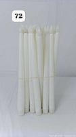 Front view of 24 white flameless LED taper candles bundled together with rubber bands showing the base and pointed tops.