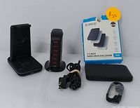 Overview of the lot showing wireless charging stand, USB hub, power cord, ORICO hard drive enclosure with USB cable and box