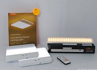 Two LED motion sensor ceiling lights illuminated beside their packaging and a rechargeable LED light bar on its box.