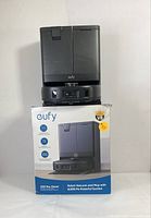 Self-emptying base unit atop original packaging showing front ejector hatch and Eufy logo