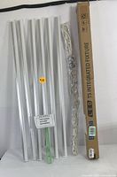 Seven LED T5 integrated fixture light bars, white with slim design, laid out side by side with cords and mounting accessories placed to the right and original product box standing upright on the right side.