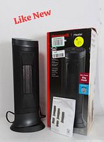 Photo of the Honeywell tower heater next to its original box and user manual, showing the heater standing upright and highlighting the slim and modern design.