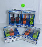 Five value packs of brand new Midland X-Talker two-way radios in original sealed packaging, showing red, black, orange, blue, and green radio colors.