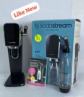 SodaStream ART sparkling water maker with the original box, reusable bottle, and user manual displayed together.
