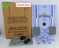 Photo of original packaging box labeled MULTIGYM A-001 next to the fitness board and included resistance bands and accessories.