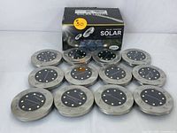 Twelve stainless steel framed solar disk lights arranged with original packaging box