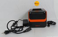 Front view of the black and orange Rongta RP332 thermal receipt printer with power and paper feed buttons visible and connected power adapter and USB cable.