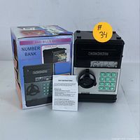 Electronic number bank safe with keypad, manual dial lock, coin and bill slots, original box and instructions displayed.