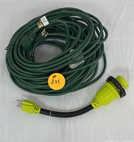 Overview of bundled green heavy-duty extension cord with attached black plug and separate yellow-green 30 amp RV adapter with locking ring.
