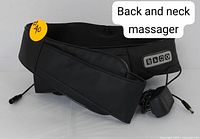Black back and neck massager folded with visible control panel and yellow pricing sticker.