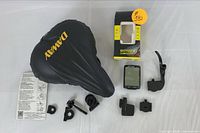 Full view of the DAWAY padded bike seat cover, bicycle computer, original computer box, and all mounting accessories on a white surface.