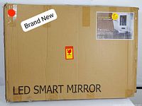 Cardboard box with label showing 'LED SMART MIRROR,' marked as brand new and with shipping and handling symbols.