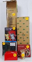 Photo shows several boxed Christmas decorations including artificial tree boxes, angel tree topper box, LED candle lights, wreath, and ornament boxes all stacked together.