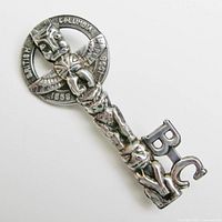 Front view of vintage sterling silver brooch depicting a skeleton key with a native totem pole figure forming the shank and circular head with inscriptions.