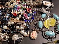Image showing assorted vintage costume jewelry including necklaces, bracelets, earrings, hair bars, and pendants in various colors and styles.