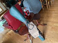 Green practice golf bag with repeating beige logo pattern, strap and padded handle observed. Bag placed near wooden floors with furniture in background.