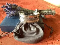 Front angled view of the sterling silver cuff bracelet resting on Silpada pouch and presentation box with lavender sprigs in background.