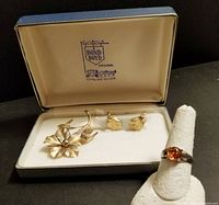 Photo showing the Bond Boyd brooch, matching leaf-shaped earrings in original presentation box, and the amber ring displayed separately on a ring holder.