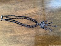 Full necklace laid flat on wooden surface showing double strand and pendant detail.