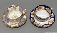 Two fine bone china teacups and saucers side by side, showing top view and ornate floral and gold detailing.