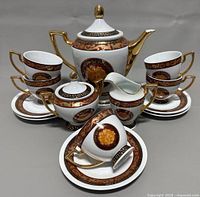 Full set of Adeline fine porcelain tea set including teapot, sugar bowl, creamer, five cups and saucers with detailed gold and burgundy pattern