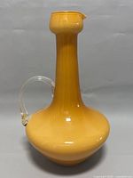 Full view of yellow Empoli art glass pitcher with clear handle showing overall shape and color.