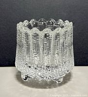 Front and side views of the clear textured glass tealight holder showing its pattern and scalloped rim.