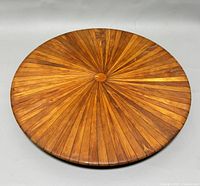 Top view of circular teak Lazy Susan showing sunburst segmented wood design with natural teak grain and color variations.