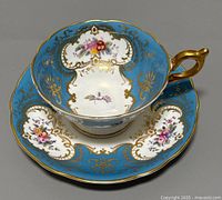Overhead view showing teacup seated in saucer, highlighting the blue background, floral pattern, and gold detailing