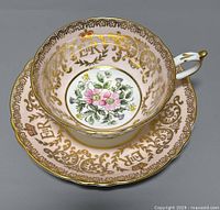 Teacup and saucer set viewed from above showing detailed floral and gold designs with royal insignia.