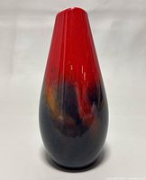 Front view of the porcelain vase showing the red top fading into a dark base with some orange highlights.