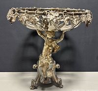 Front view of vintage silverplated cherub centerpiece showing the cherub figure holding the ornate bowl with grapevine decoration and three curved feet base.