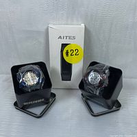 Two SKMEI digital sports watches in metal tins wrapped in plastic and AITES fitness tracker box in the center