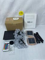 Photo of both solar lighting sets laid out with packaging and accessories including remote control, stakes, and instruction manual.