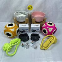 Full lot display showing 2 ceramic pet food bowls with wooden stands, 2 crocheted ball toys, 2 no bark collars with accessories, and 2 braided rope tug dog toys.