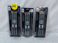 Photo of three Monster 8-in-1 universal remotes in sealed packaging side by side.