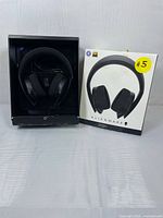 Alienware 310H gaming headset inside open display box next to closed product box with yellow sticker